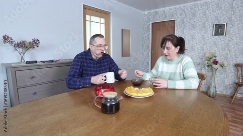 Mature couple enjoys breakfast with tea and cake at an oval dining table.
