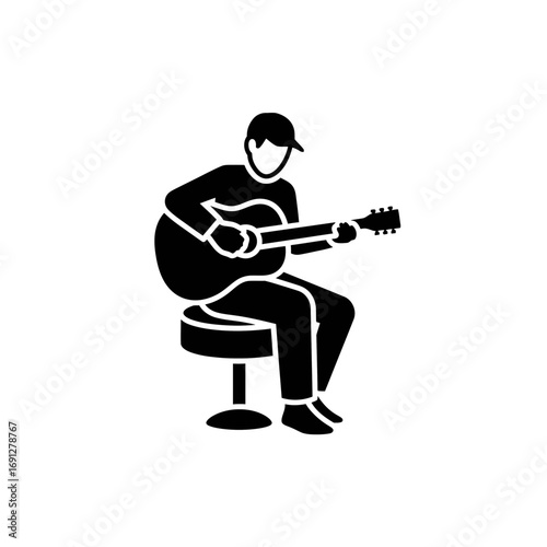 Guitarist playing music while seated on a stool