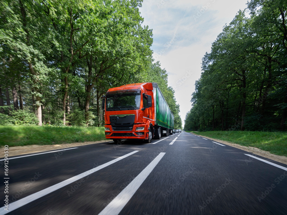 Obraz premium Orange truck with green trailer captured with motion blur effect showing movement and speed
