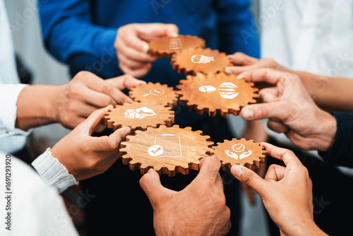 Hands join together to hold wooden gears, showcasing collaboration and teamwork in a business environment. Each gear represents ideas and concepts essential for success. Amity
