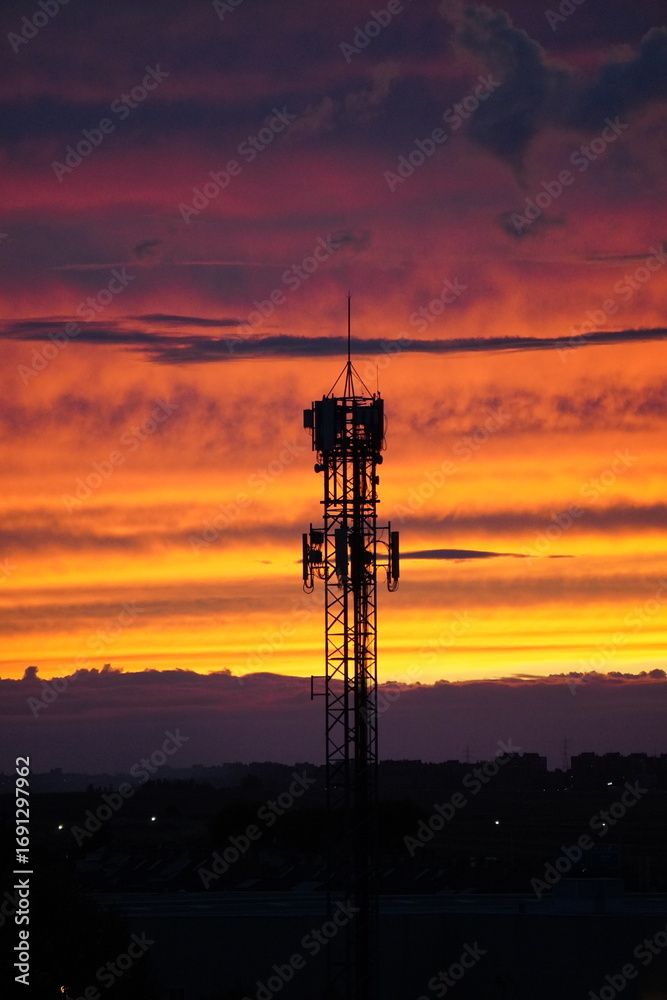 Naklejka premium Telecommunication tower at sunset with dramatic sky