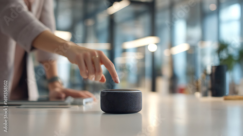 Person interacting with a smart speaker on a modern office desk