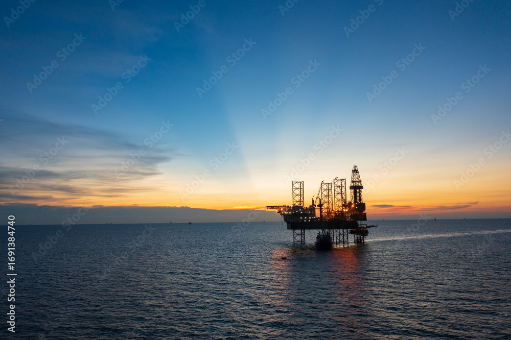 Obraz premium Aerial view of offshore jack up rig in a shipyard during sunset for oil and gas exploration and production. 