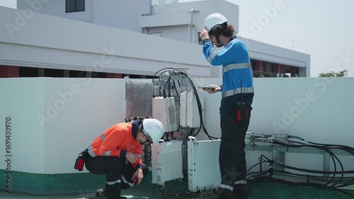 Engineers inspecting rooftop electrical equipment
