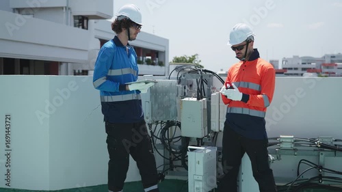 Engineers inspecting rooftop electrical equipment
