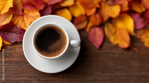 A cup of coffee with autumn leaves on wooden background