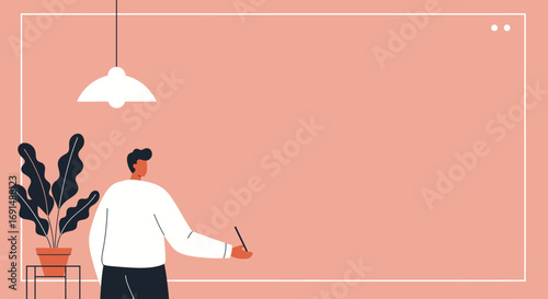 Man holding a pen in a modern, minimalist room with a plant and lamp, representing creativity, remote work, online learning, or business planning.