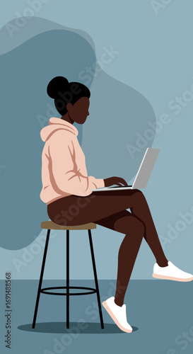 Young Black woman focused on her laptop, sitting casually on a stool. Represents remote work, online learning, freelancing, and modern productivity.