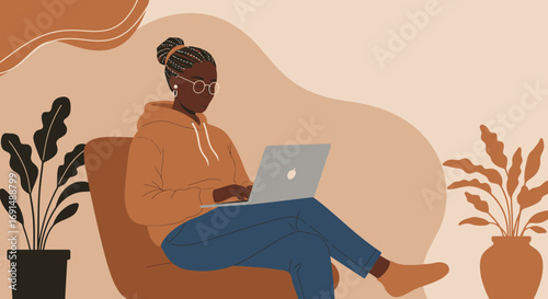 African American woman working remotely on her laptop in a comfortable home environment. Represents modern productivity, online learning, and flexible lifestyle.