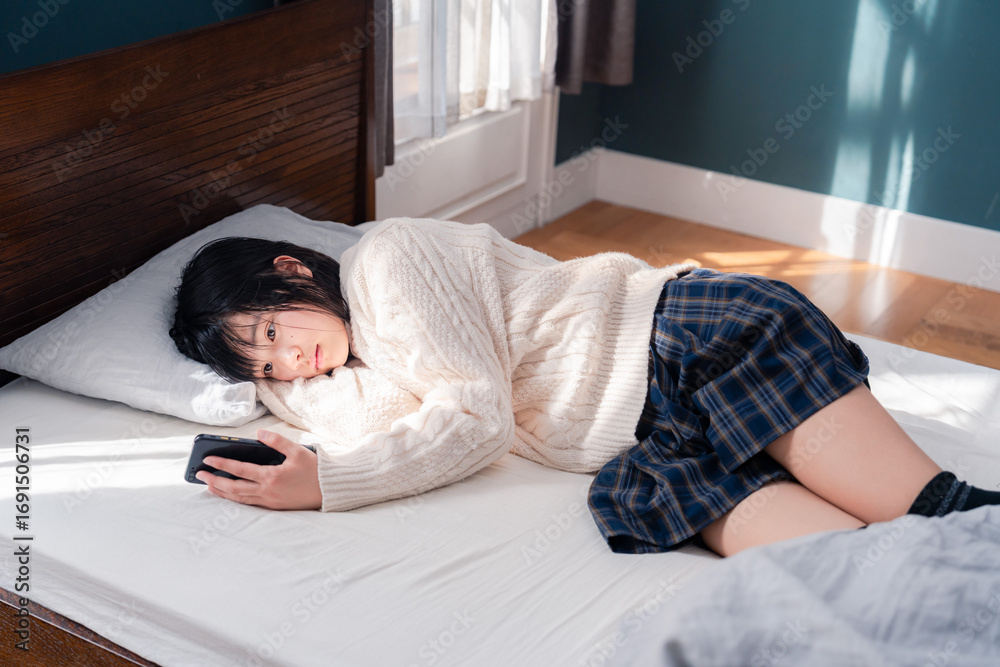 © maroke - ベッドに寝転がってスマホを使う思春期の少女 © maroke - ベッドに寝転がってスマホを使う思春期の少女