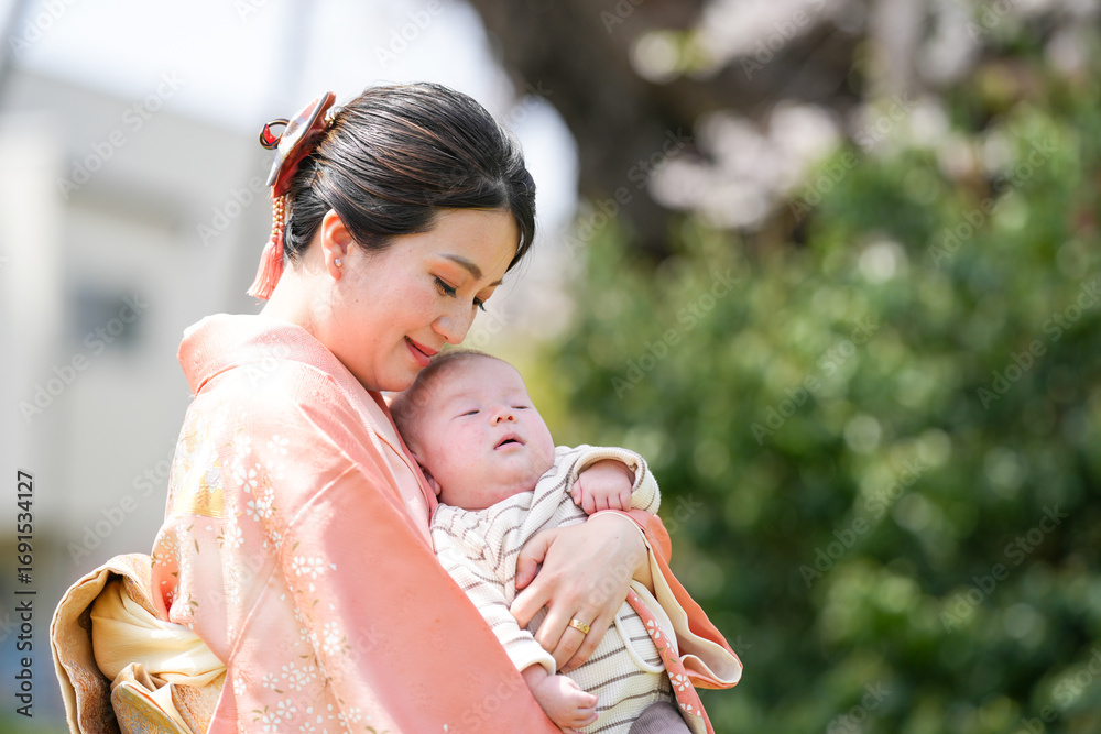 Obraz premium A woman is holding a baby in her arms. The baby is sleeping and the woman is smiling. Concept of warmth and love between the mother and child