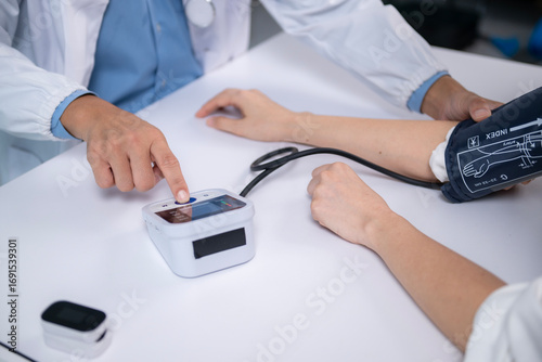 Doctor measuring blood pressure of patient using digital sphygmomanometer in clinic