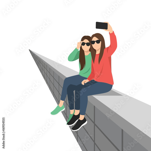 Two friends take a selfie while perched atop a long wall, enjoying a carefree moment together.