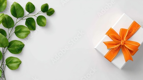 White gift box with an orange ribbon sits next to a leafy branch. The arrangement sits on a crisp white background, creating a sense of freshness