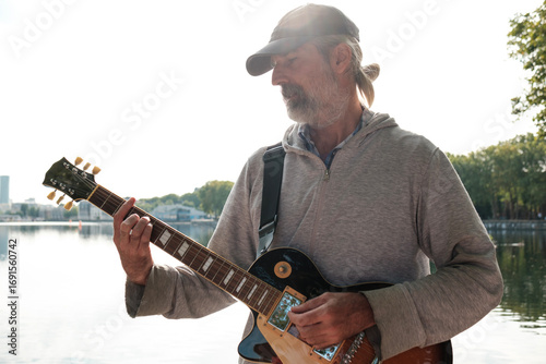 Photography Senior musician playing electric guitar by the lake