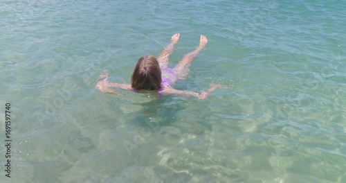 Woman having fun swimming in turquoise warm ocean. Sunny day.