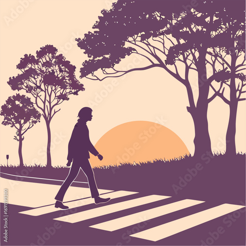 Man walking across a crosswalk at sunset.