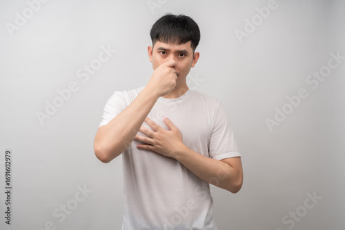 Fotografi A young man with a disgusted expression pinches his nose, reacting to a foul smell or air pollution