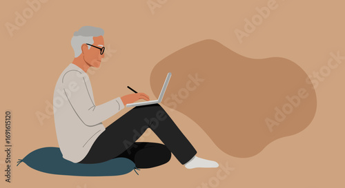 Senior man with glasses sits comfortably, focused on his laptop, actively typing or writing with a pen. Represents remote work, online learning, or digital engagement for modern elders.