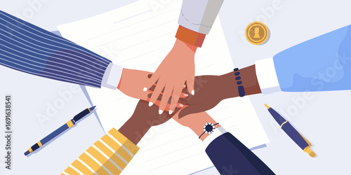 Diverse team of professionals stacking hands together in a circle over documents and pens symbolizing unity and collaboration