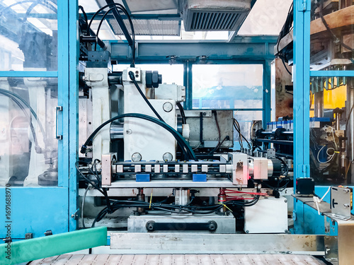 Blow molding machine producing clear plastic bottles on factory production line.