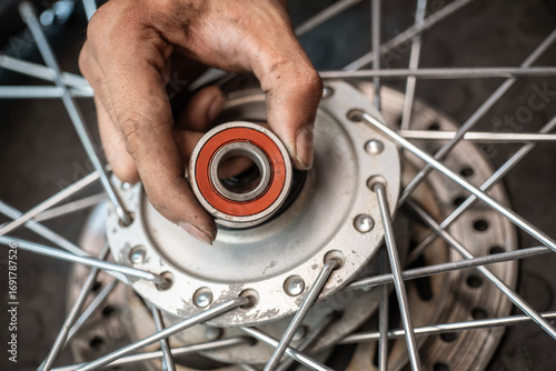 Mechanic check and replace Motorcycle wheel bearings , working in garage .maintenance and repair motorcycle concept .selective focus