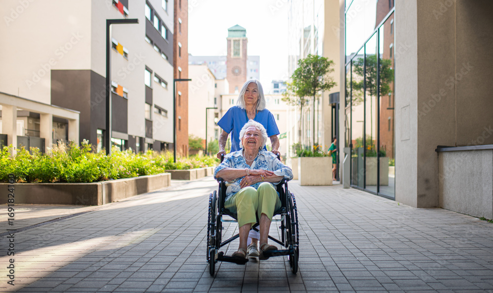 Obraz premium Aging woman in wheelchair enjoying fresh air with care assistant