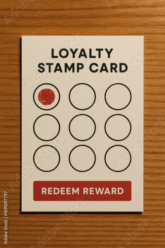 Loyalty stamp card with one red mark and redeem reward button on wooden surface
