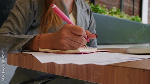 close up of a woman's hand writing plans in her book on her desk