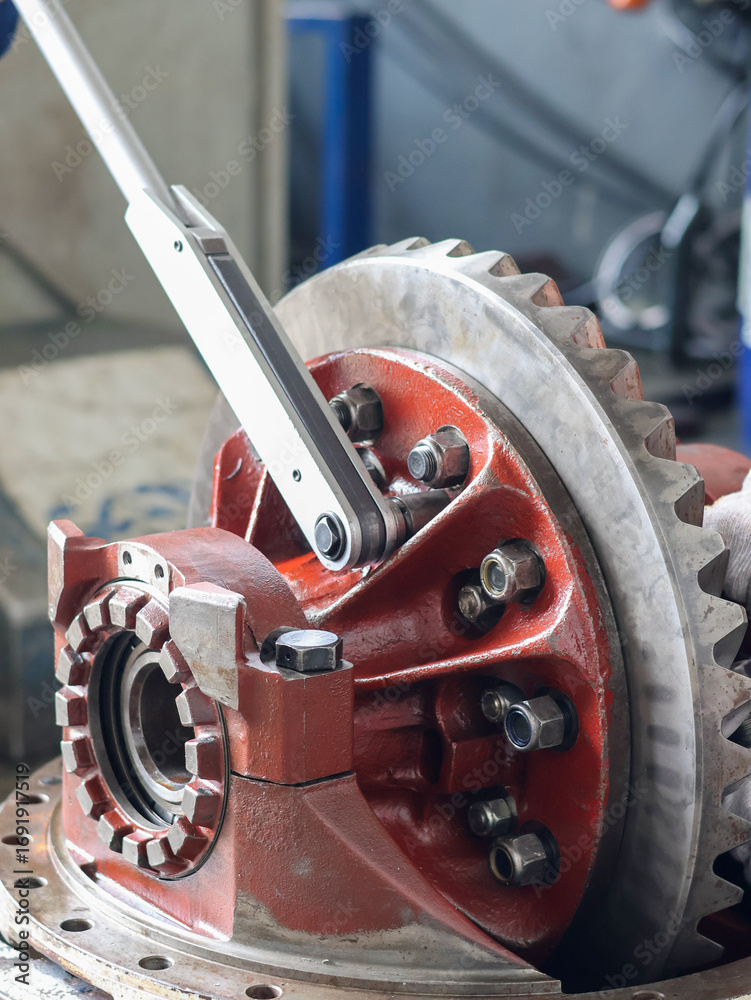 Φωτογραφία ​A mechanic uses a large torque wrench to tighten bolts on a differential crown gear, showcasing industrial repair and machinery maintenance