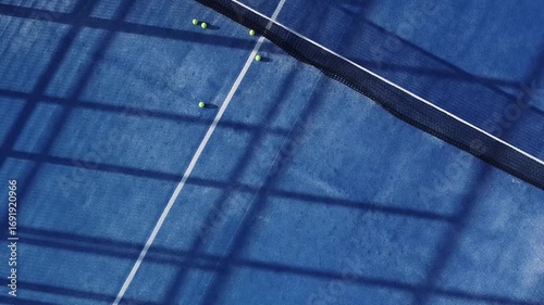 Aerial drone video descending over a blue padel court with tennis balls A Modern Sport