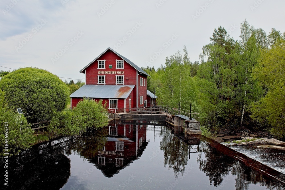 Obraz premium The old wooden Joutsenkoski mill (Joutsekosken mylly) on cloudy spring weather, Ylämaa, Finland.