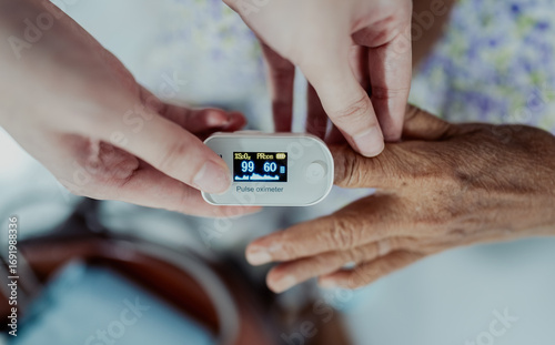 Close-up of nurse checking oxygen level with pulse oximeter on elderly woman’s finger. Medical technology, healthcare, diagnosis, and patient monitoring at home.