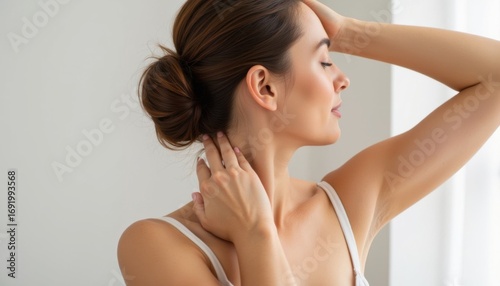 Young woman relaxing with hand on neck by window in natural light  