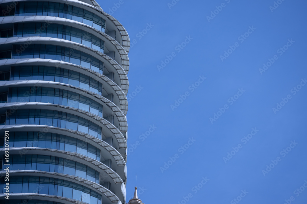 Naklejka premium A section of a modern building with many rectangular glass windows reflecting the clear