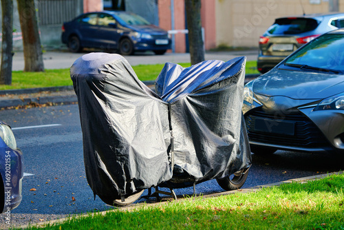 Принти на полотні Motorbike parked under black weatherproof cover, providing sun shield, dust guard and wind and rain resistant