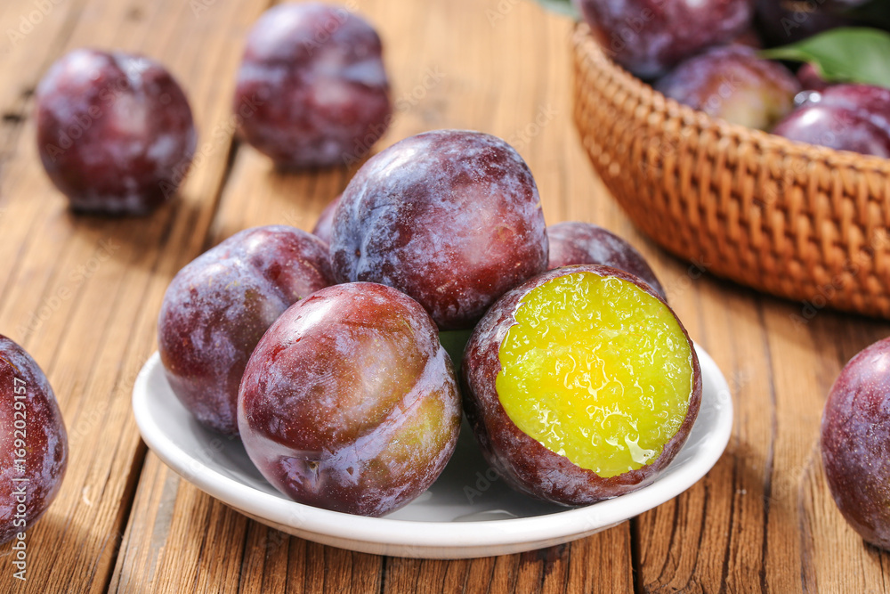 Obraz premium Fresh Red Plums with Yellow Flesh on Wooden Table - Sweet Summer Fruit Display
