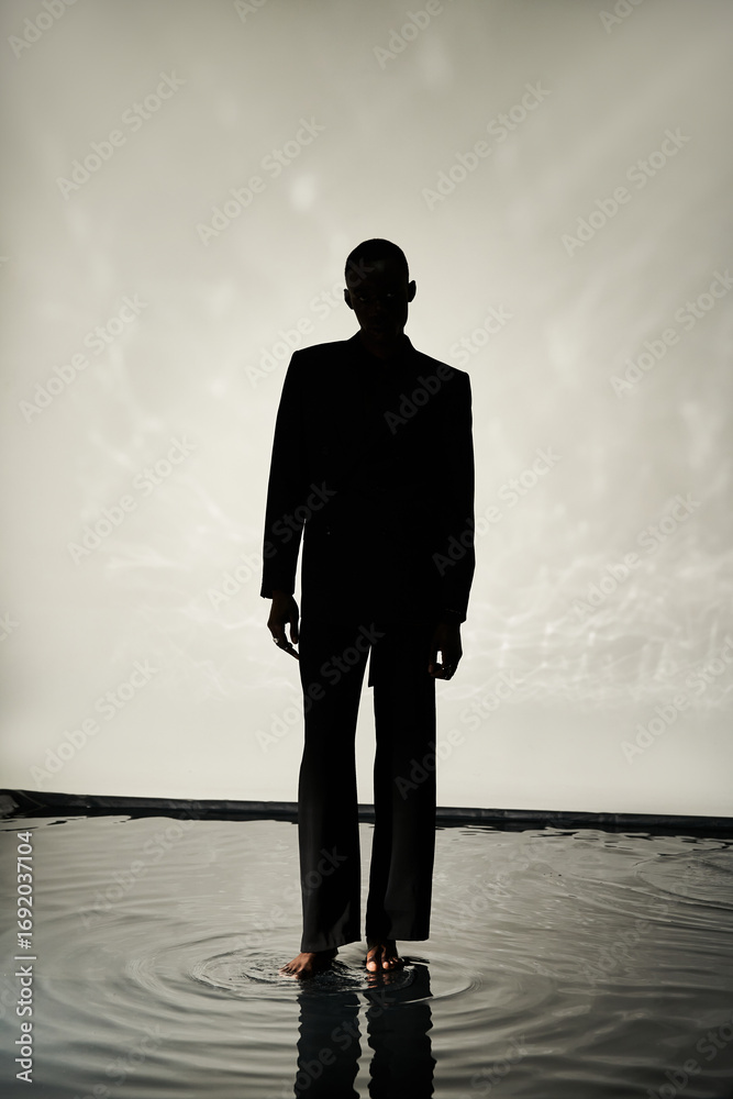 Obraz premium Elegant young man stands gracefully in water against a minimalist backdrop
