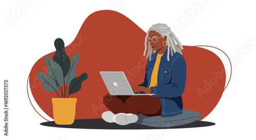 Mature African American woman using a laptop for remote work or learning from the comfort of her home office.