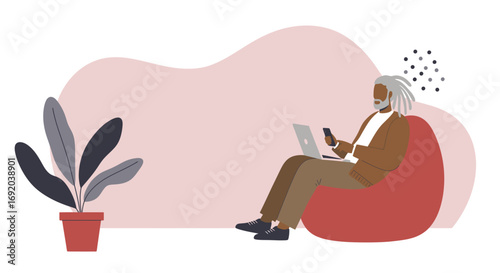 Elderly Black man with dreadlocks comfortably working remotely on a laptop and smartphone from a bean bag chair at home. Modern lifestyle, technology, and flexible work concept.