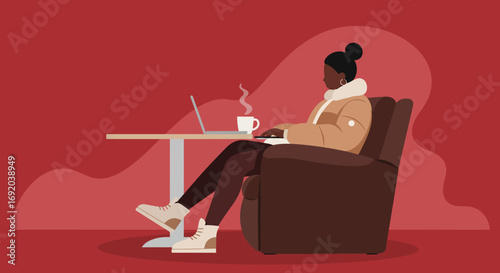 Woman in cozy jacket works on laptop with steaming coffee in an armchair, depicting remote work, comfort, and digital lifestyle.