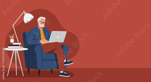 Senior man focused on his laptop while comfortably seated in an armchair at home. Represents remote work, digital literacy, and modern senior lifestyle.