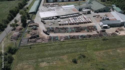 Industrial lumber yard captured from above shows piles of timber prepared for further processing. The site is active and well-structured, highlighting the scale of wood production.