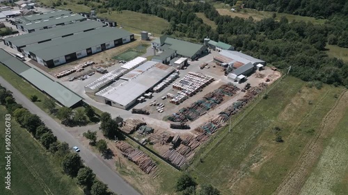Aerial view of a timber storage yard with neatly organized logs and processed wood ready for distribution. A forklift moves through the area, ensuring smooth industrial workflow.