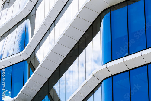 Futuristic office building with curved white structures and reflective blue glass creating fluid, modern architectural design.