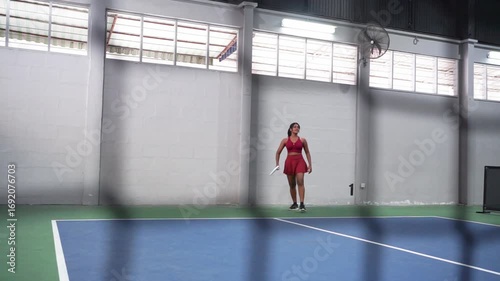 Female pickleball player tossing paddle in indoor court