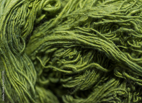 Green wool yarn as background. Close-up. Selective focus.