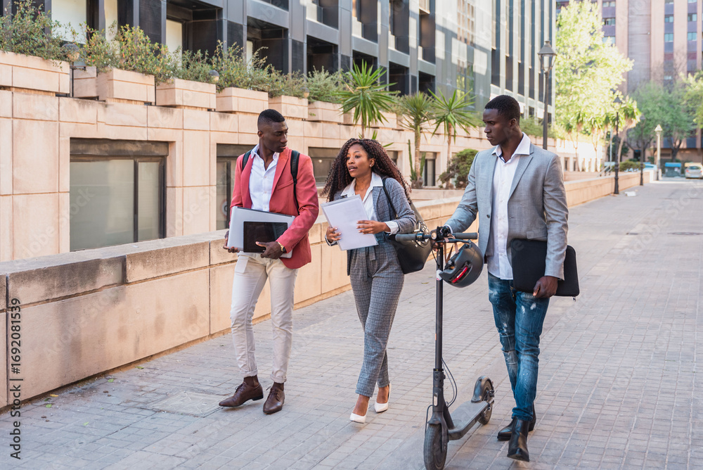Fototapeta premium Multiracial diverse business teamwork walking and talking on city street with electric scooter