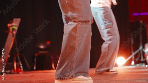 Young musicians performing contemporary christian music, wearing baggy jeans and sneakers, moving rhythmically under warm stage lighting during worship night