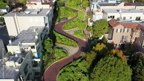Aerial view of the winding Lombard Street, a vibrant ribbon of red brick framed by lush greenery and diverse architecture, San Francisco, California, United States.